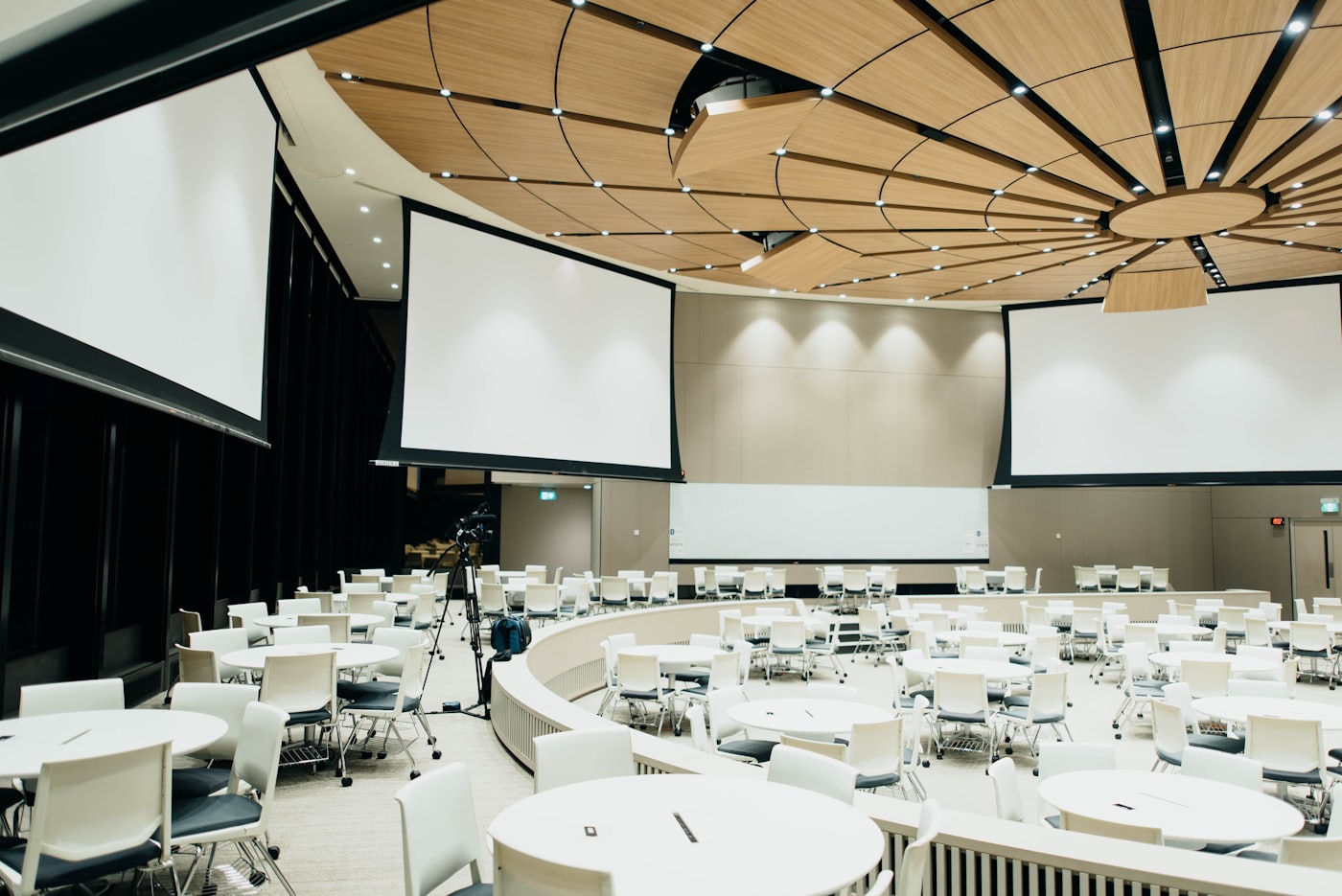 Conference hall set with round tables and projection screens